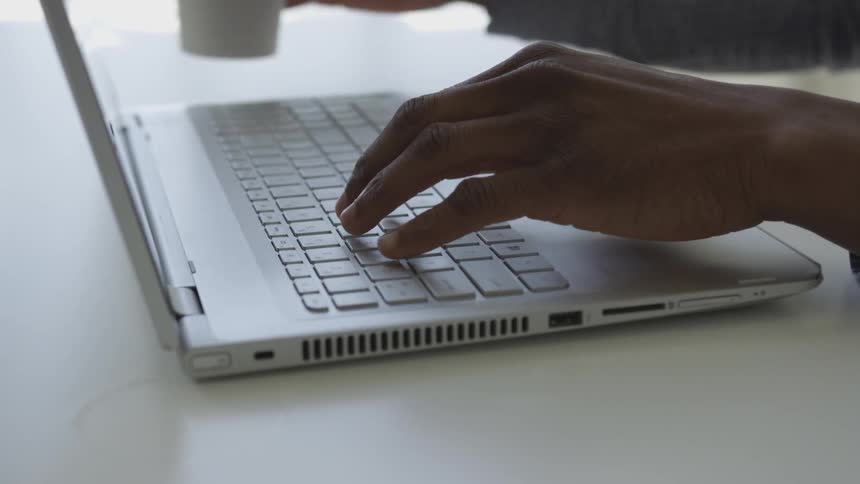 Woman typing on laptop and drinking coffee