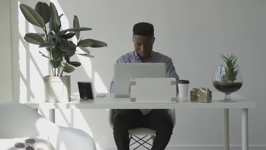 Young black man works on laptop on desk