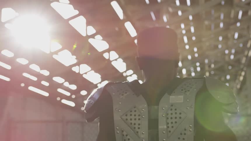 Man wearing football gear walks under the bleachers of a stadium