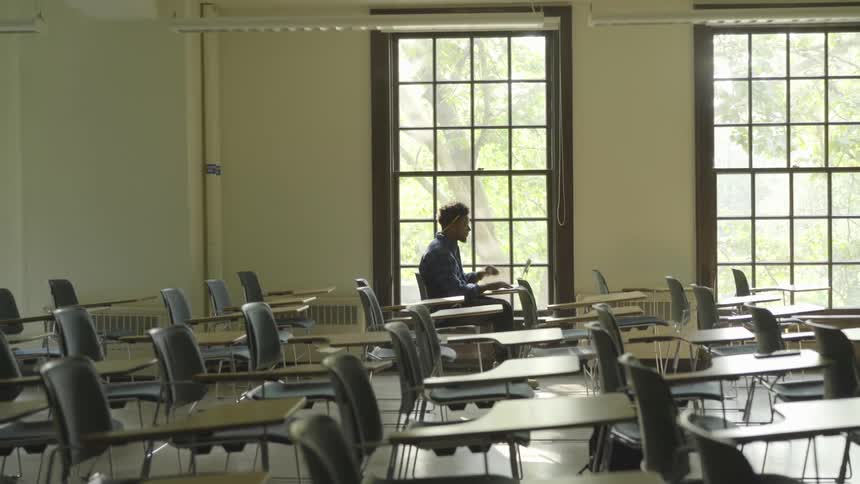 A young man sits at a desk typing on a laptop