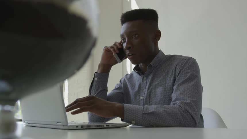 A man is talking on a phone at the desk