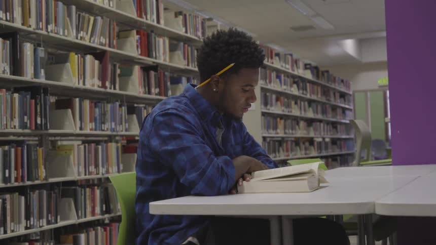 Man sitting at a desk on the library reading a book