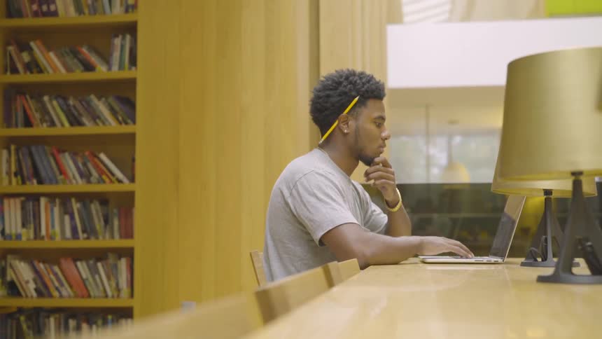 A man sits at a table and works on a laptop