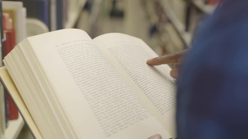 A person reading from a thick textbook