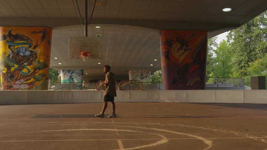 Young man standing in standing on basketball court holding a ball