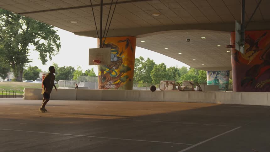 A person plays basketball on a covered court