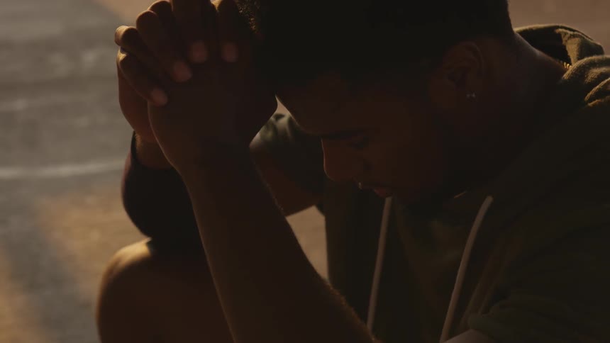 A man puts his hands together then holds them to his head