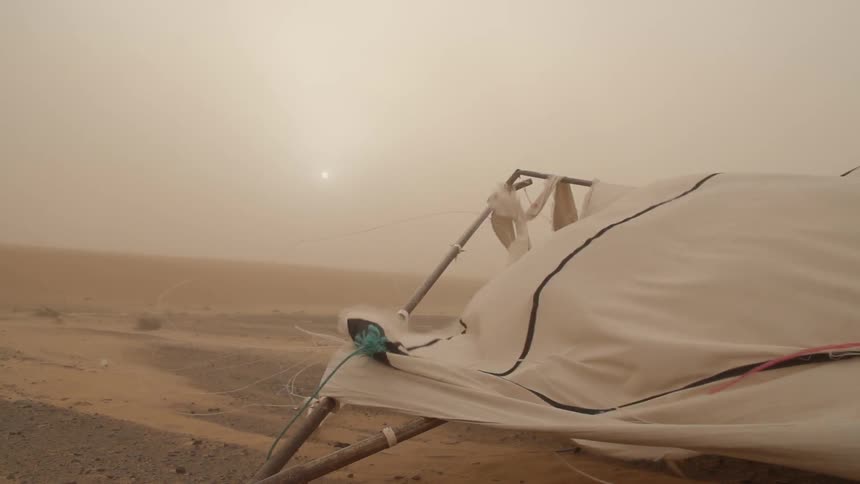 A ripped tent flapping in a sand storm