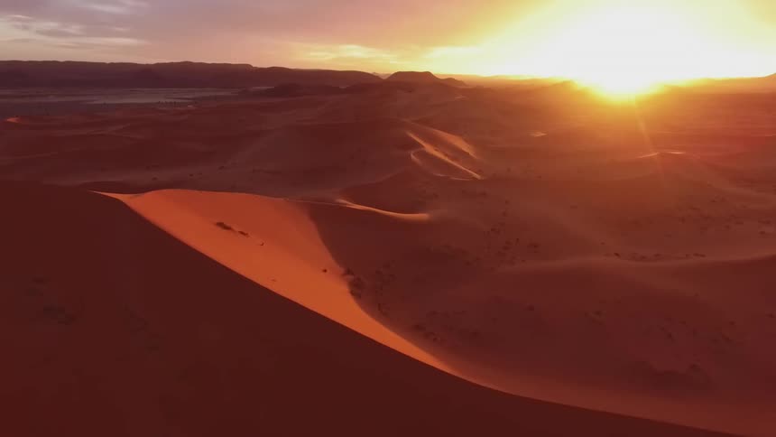 The sun sets over sand dunes and ridges