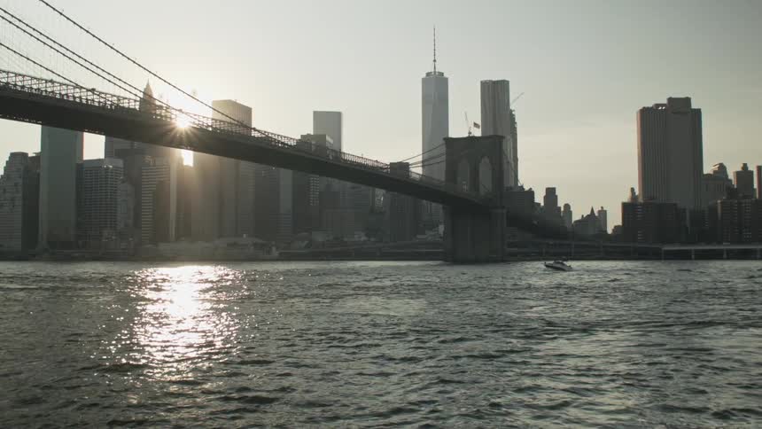 Boat navigating under a big bridge going into a large city