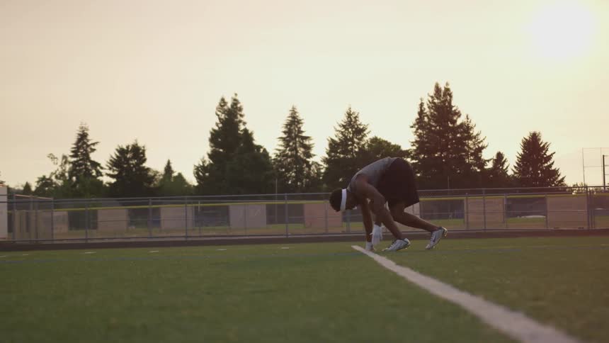 A man stands at the white line of an outdoor court get set and sprint off