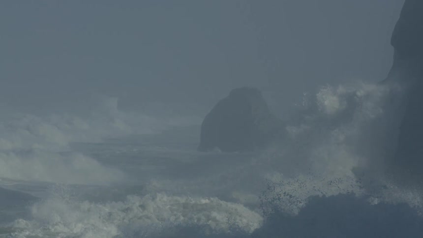 Large waves crashing against cliffs and spraying into the air