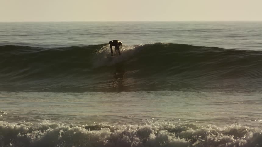 A surfer paddles and catches a wave for a ride