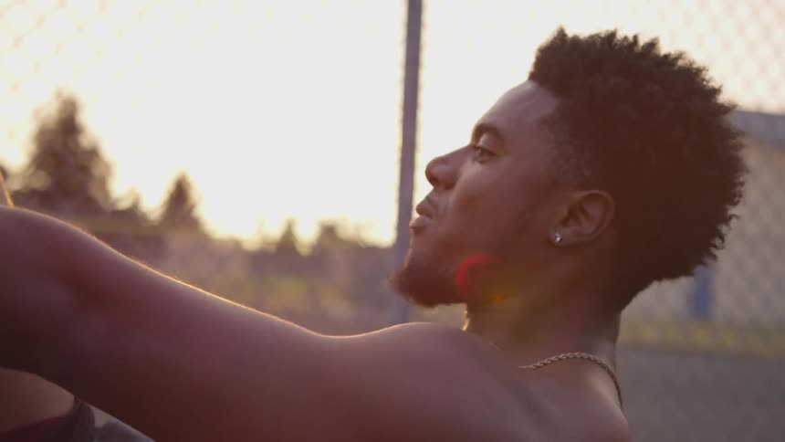 Black man with a beard works out near the fence