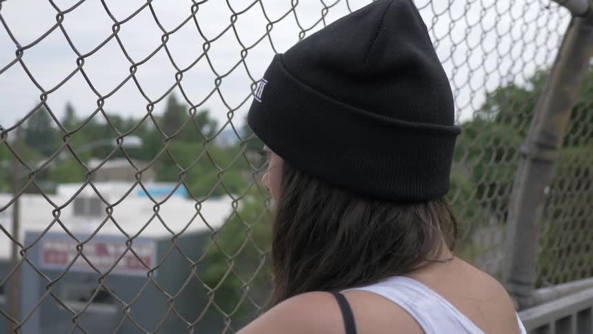 A woman with a knit hat stares through a fence
