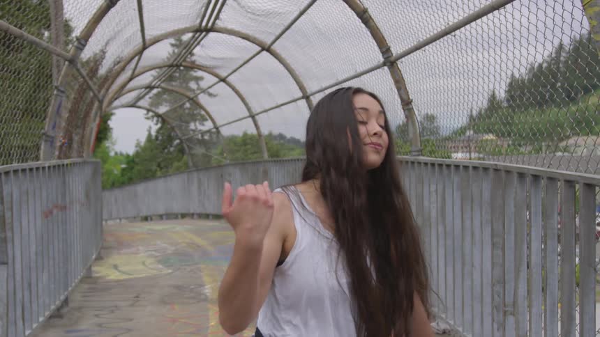 A woman dances on a pedestrian walkway