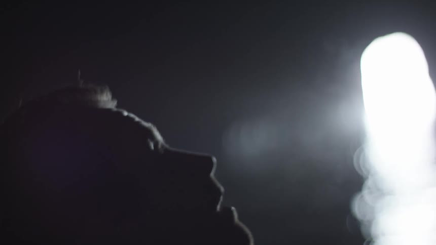 Man looking upwards and blowing out visible breath in a massive sea cave