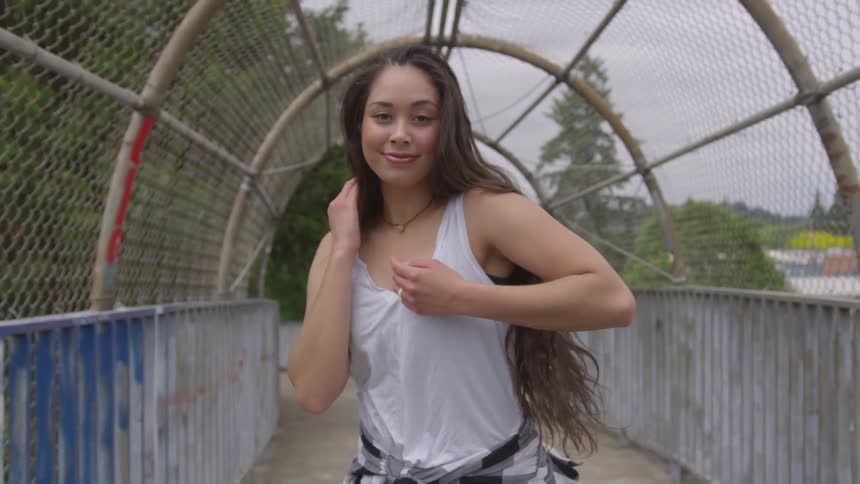 Young woman dancing across an overpass