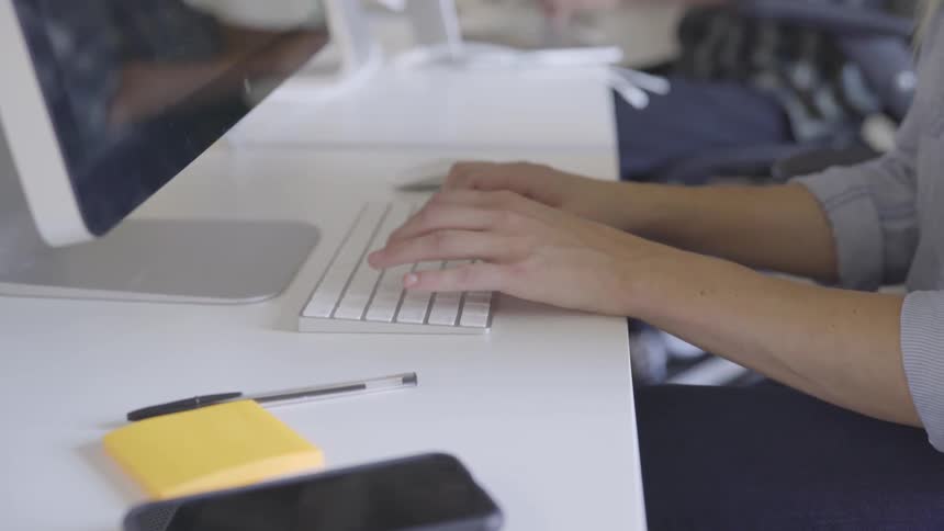 Woman types on the keyboard in the office during daylight