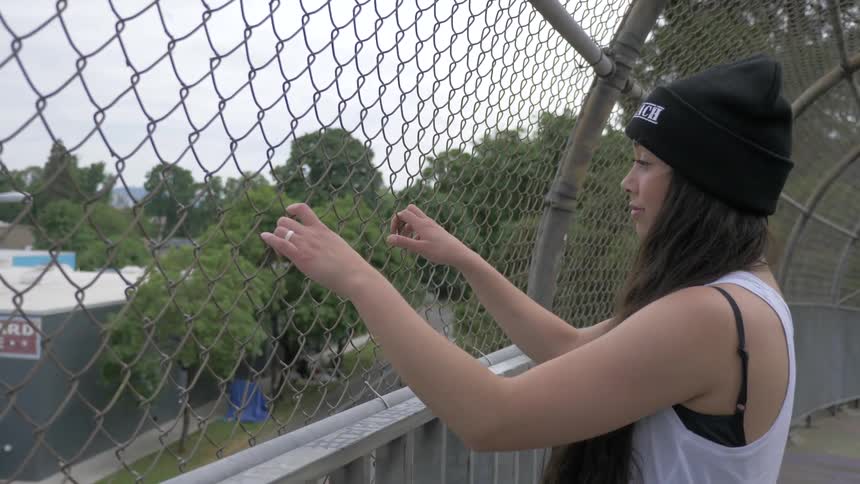 A woman standing outside pulling on a fence