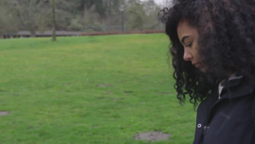 A woman is looking down walking on the field