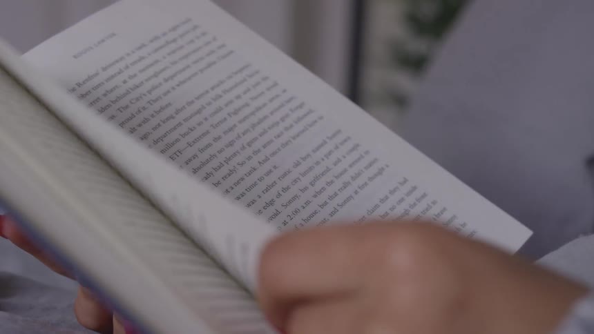 A woman turns the page in a book