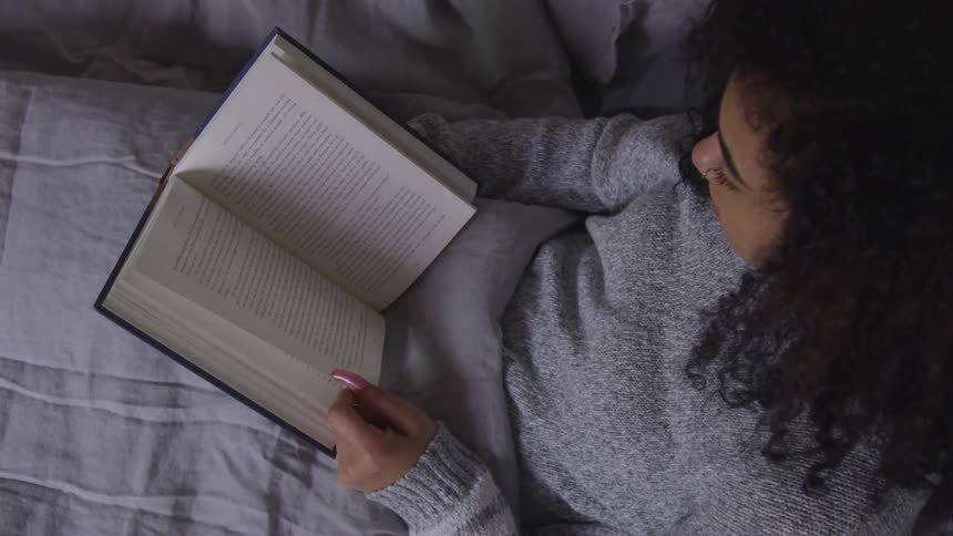 A woman laying in bed reading a book