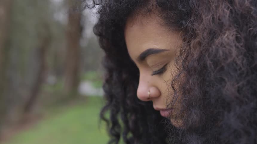 Woman with piercing on nose sitting outside looking down