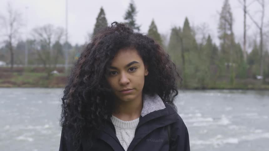 A woman stands in front of a river