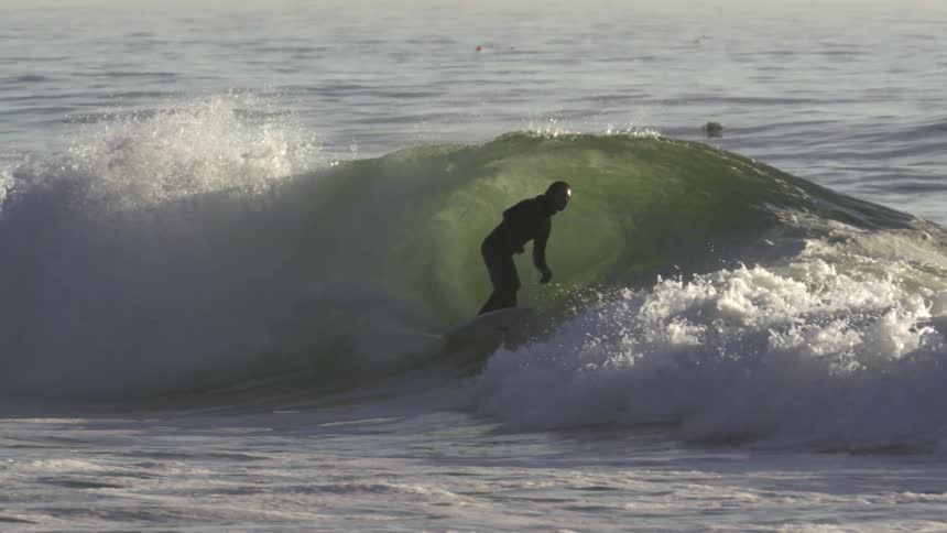 A man surfs a wave on a sunny day