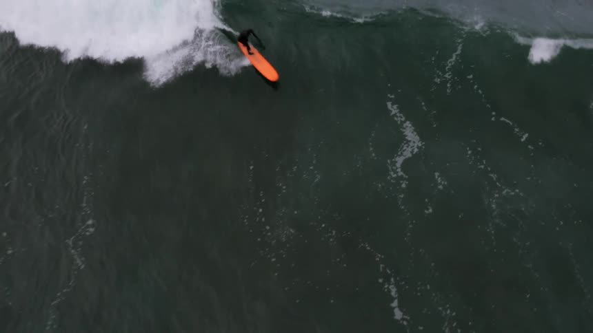 Epic aerial shot looking straight down of a surfer riding a wave in the ocean