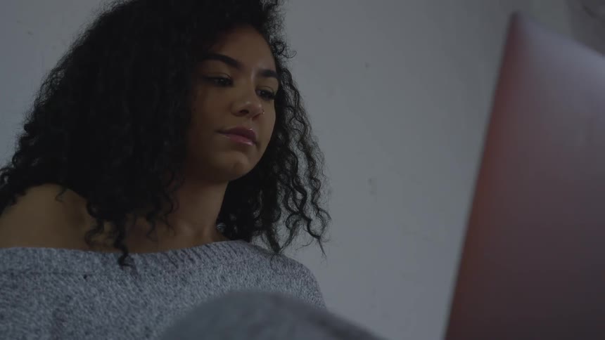 A woman with curly hair uses a laptop indoors