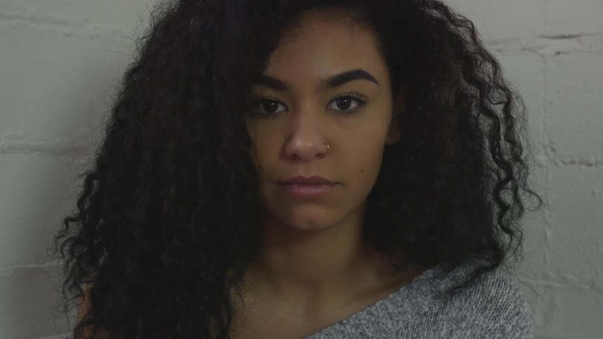 A woman is staring forward near the wall