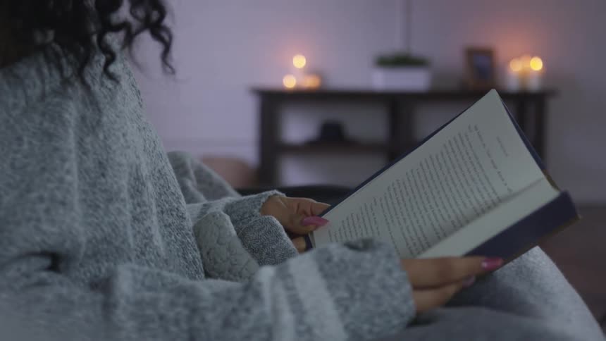 Woman reading a book on a candle lit room