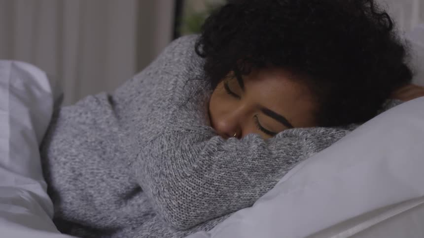A young lady under a blanket is taking a nap on a pillow