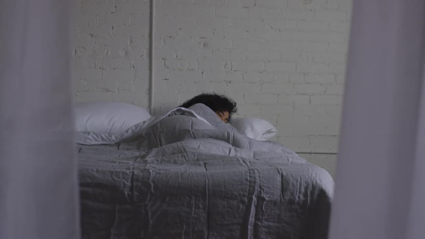 A black woman sleeps in a bed