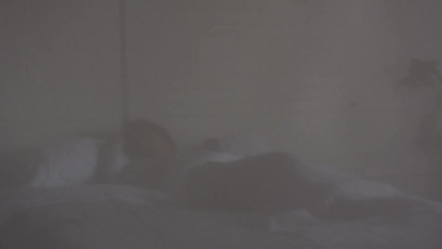 A woman arises slowly in bed