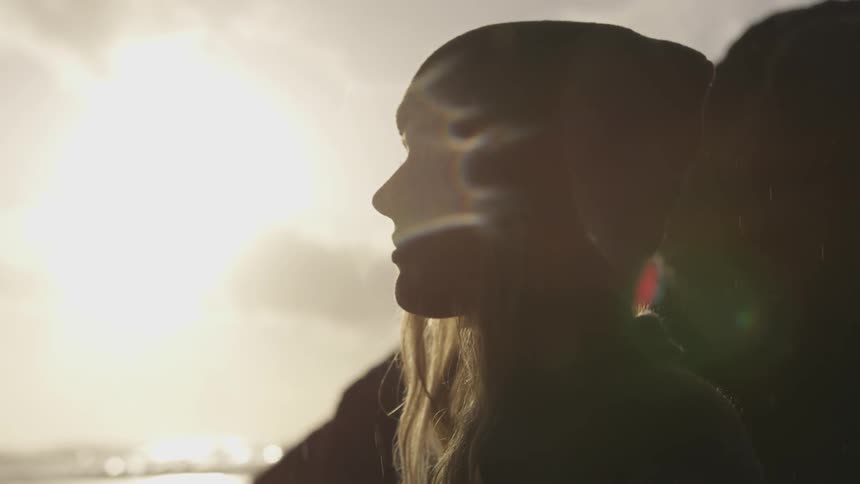 A woman standing on the shore during sunrise in the rain