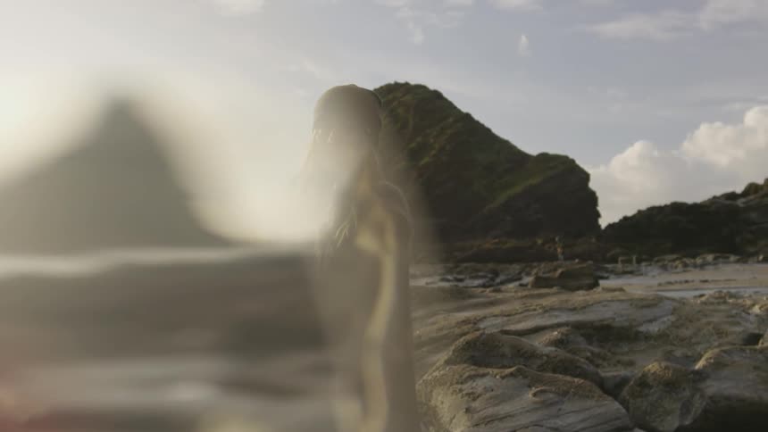 A blurry person standing near a rock strewn beach