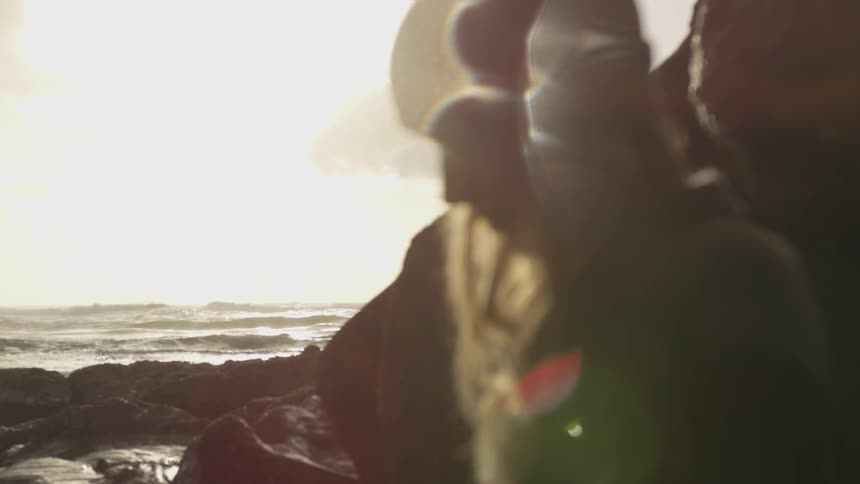 A white woman with a hat by rocks on a beach