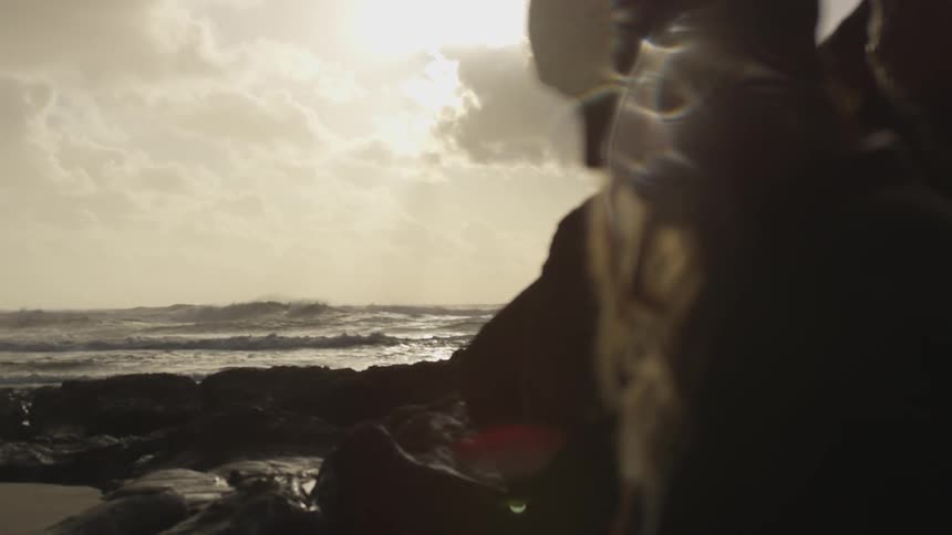 Woman stands near the rocks at the beach