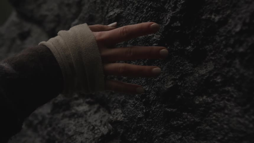 Woman's hands touching a large rock