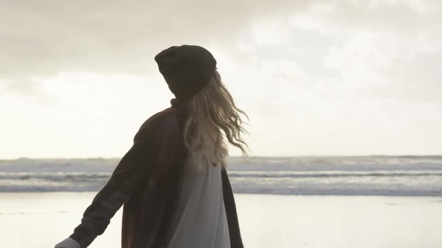 A female caucasian on a beach spinning around