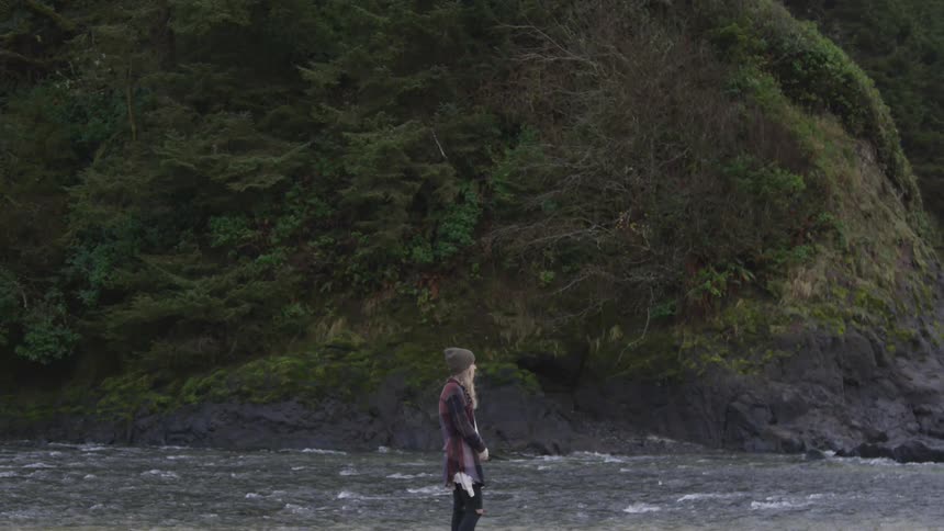 A woman stands next to a river