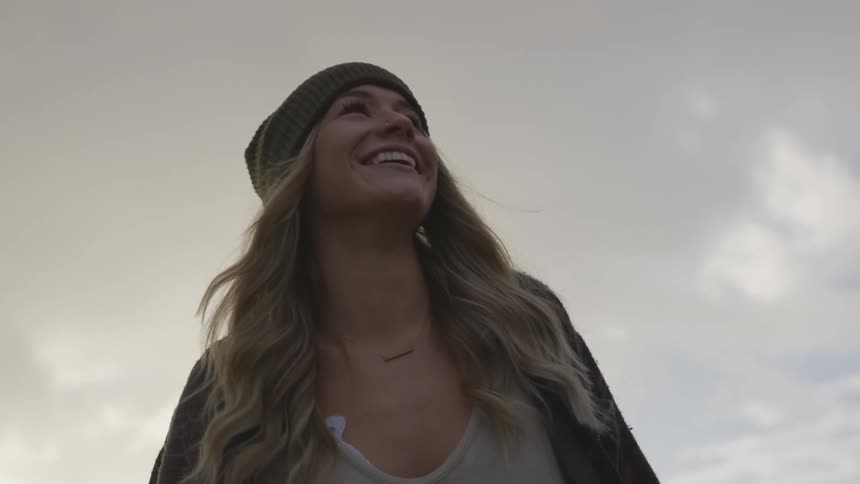 A woman turns around as she looks into the air and smiles