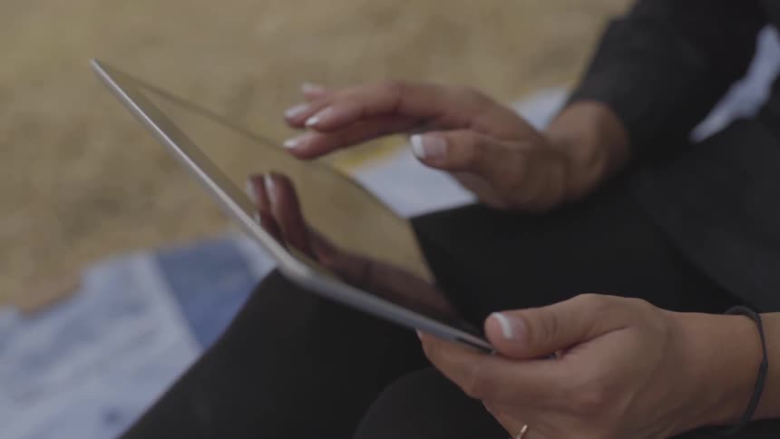 Brunette woman sits and uses tablet indoors during daylight