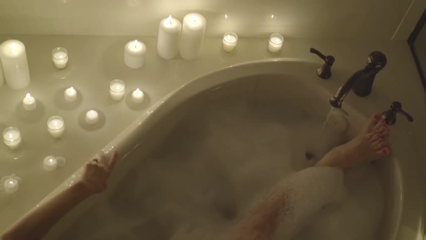 A woman sitting in a candlelit bubble bath