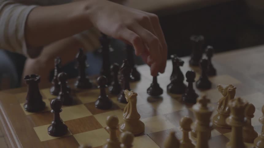 A person moves a chess piece in a game