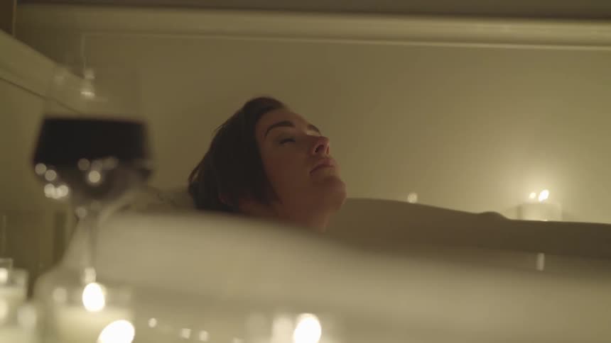 A woman relaxes in a candle lit bath