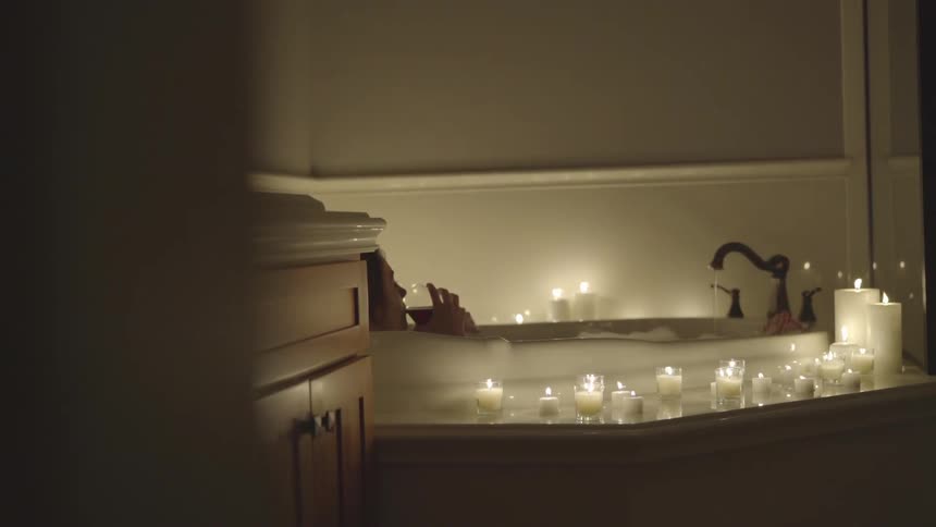 A woman drinks wine while sitting in a bathtub